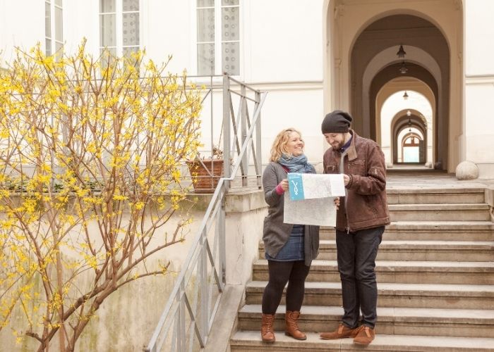 Eine Frau und ein Mann gehen in Wien spazieren und schauen auf der Fußwegekarte nach, wo sie sich gerade befinden.